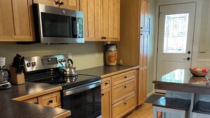A kitchen with wooden cabinets, a stainless steel stove, a microwave, and a refrigerator. - 3-bedroom condo in adorable Elk Rapids with AC and comfort - One block to beach (Elk Rapids)
