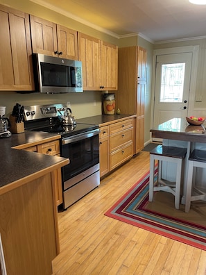 A kitchen with wooden cabinets, a stainless steel stove, a microwave, and a refrigerator. - 3-bedroom condo in adorable Elk Rapids with AC and comfort - One block to beach (Elk Rapids)