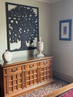 Ein Holzkabinett mit Schubladen, eine dekorative Vase und ein Wandbild.