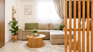A living room with a sofa, a round coffee table, a plant, and a wall-mounted TV. - The Pine -stylish Thessaloniki Stay Priv Parking (Pavlos Melas)
