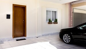 A modern house with a wooden door, a window with plants, and a parked car. - The Pine -stylish Thessaloniki Stay Priv Parking (Pavlos Melas)