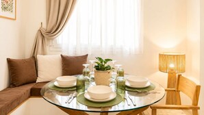 A dining area with a glass table, green placemats, white plates, and a potted plant. - The Pine -stylish Thessaloniki Stay Priv Parking (Pavlos Melas)