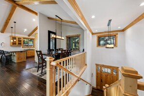 A spacious kitchen with wooden cabinets, a dining area with a large table, and a staircase leading to an upper level. - The Alpine Green Lodge (South Lake Tahoe)