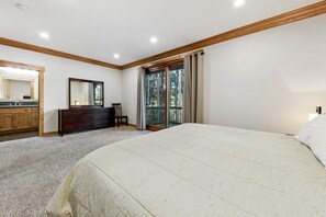 Une chambre à coucher avec un grand lit, une commode, un miroir et une porte-fenêtre coulissante donnant sur un balcon.