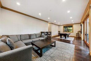 Un salon spacieux avec un canapé d’angle, une table basse et une table de billard.