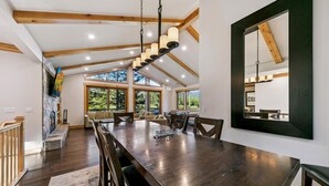 Uma sala de jantar ampla com uma mesa comprida, várias cadeiras e um lustre moderno.
