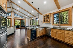 A modern kitchen with wooden cabinets, a central island, and large windows. - The Alpine Green Lodge (South Lake Tahoe)