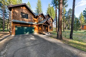 A two-story log cabin with a garage, surrounded by a forest. - The Alpine Green Lodge (South Lake Tahoe)