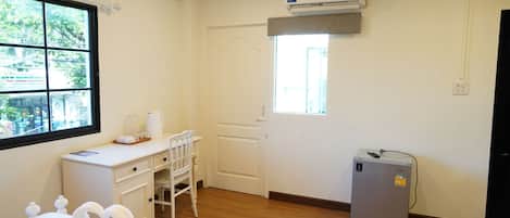 A hotel room with a bed, a desk, a chair, an air conditioner, and a window with a view.