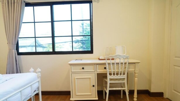 A bedroom with a bed, a desk, a chair, a window with a view, and a door. - RQ Opsian Ratchada Service Apartments (Bangkok)