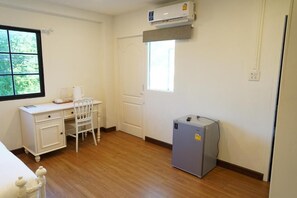 A room with a desk, chair, window, and a small refrigerator. - RQ Opsian Ratchada Service Apartments (Bangkok)