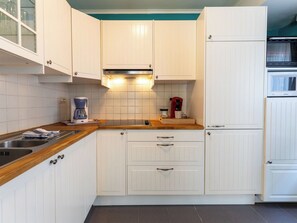 Eine Küche mit weißen Schränken, einer Holz Arbeitsplatte, einer Kaffeemaschine und einer Mikrowelle.