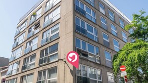 A multi-story building with a modern architectural design, featuring a mix of window styles and a visible balcony on the upper floors. - Cosy apartment for 6 people with WIFI and TV (Blankenberge)