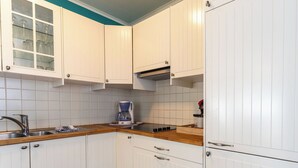 A kitchen with white cabinets, a coffee maker, a sink, and a stove. - Cosy apartment for 6 people with WIFI and TV (Blankenberge)