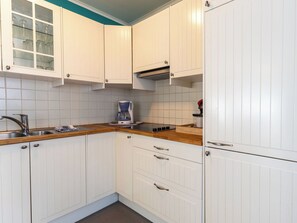 Eine Küche mit weißen Schränken, einer Kaffeemaschine, einem Spülbecken und einem Herd.
