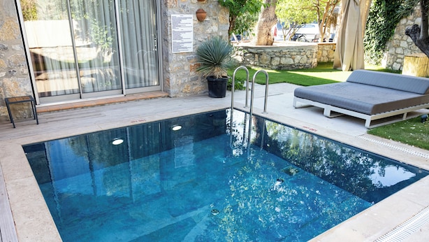 Una piscina con fondo in vetro, una sedia a sdraio e una pianta in vaso.