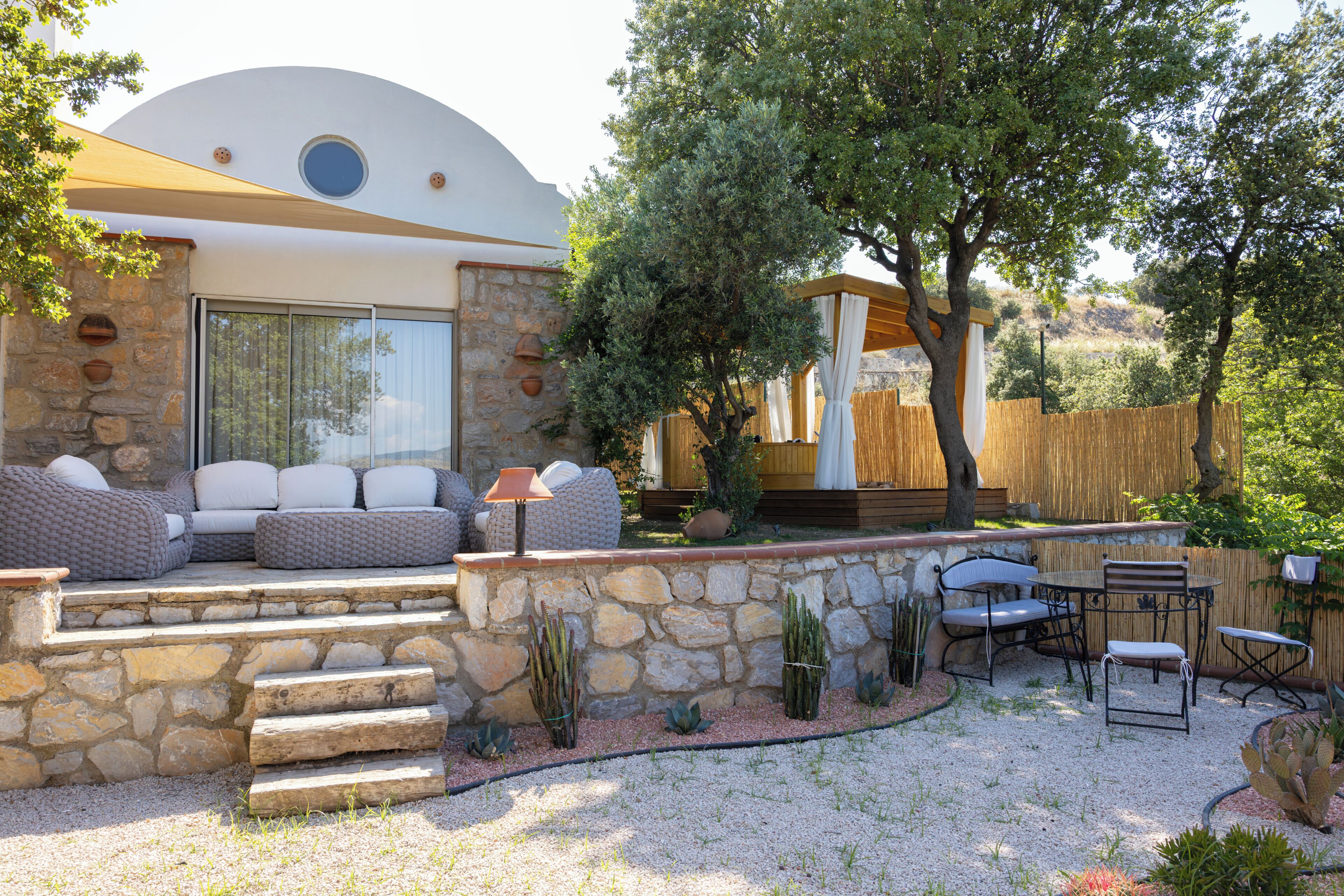 A modern outdoor seating area with stone steps, a wooden pergola, and a variety of plants.