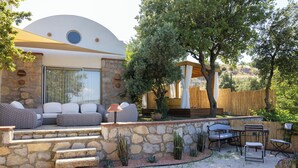 Un'area relax all'aperto moderna, con gradini in pietra, un pergolato in legno e diverse piante.