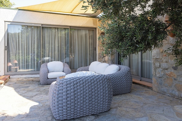 A patio with two grey woven sofas, a stone floor, and a large sliding glass door.