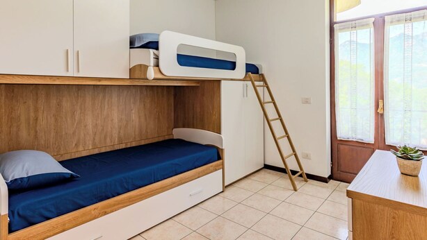 Een kamer met stapelbedden, een bureau, een ladder en een deur voorzien van gordijnen.