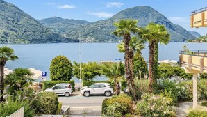 Un espace de stationnement avec des voitures, une vue dégagée sur un lac et des montagnes en arrière-plan.