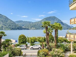 Ein Parkplatz mit Autos, Blick auf einen See und Berge im Hintergrund.