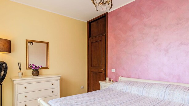 Une chambre à coucher avec un lit, une commode, un miroir et une porte.