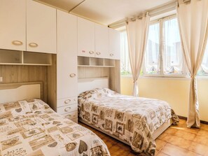 Ein Schlafzimmer mit zwei Betten, einem Kleiderschrank und einem Fenster mit Vorhängen.