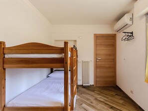Ein Stockbett in einem Raum mit Heizkörper, Holztür und Wand-Klimaanlage.