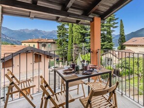 Ein Balkon mit Tisch, Stühlen und Blick auf Berge und Häuser.