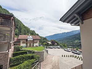 Ein Gebäude mit einem geneigten Dach, einer gepflasterten Auffahrt und einem Parkplatz mit Autos.