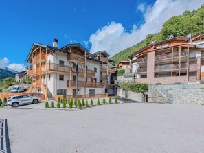 Een hotel met meerdere verdiepingen, balkons, een stenen muur en een heldere lucht.