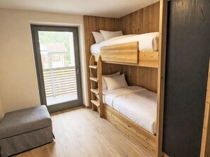 Ein Schlafzimmer mit Etagenbetten und einer Schiebetür, die auf einen Balkon führt.