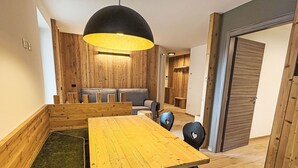 Ein Essbereich mit Holztisch und -stühlen, einer schwarzen Pendelleuchte und einer Holzwand.