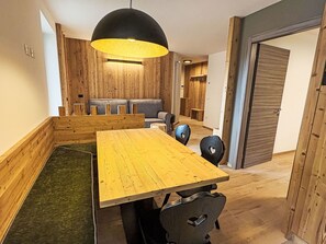 Ein Essbereich mit Holztisch und -stühlen, einer schwarzen Pendelleuchte und einer Holzwand.