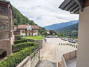 Ein Hotel mit steinverkleideter Fassade, einem Parkplatz und Blick auf Berge.