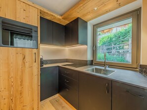 Eine moderne Küche mit Holzbalken, einem Einbauofen, einem großen Fenster und einem Spülbecken.