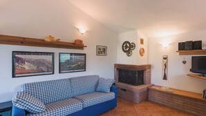 A living room with a blue checkered sofa, a fireplace, and two framed pictures on the wall. - Beautiful private villa for 4 people with WIFI and terrace (Bagnone)