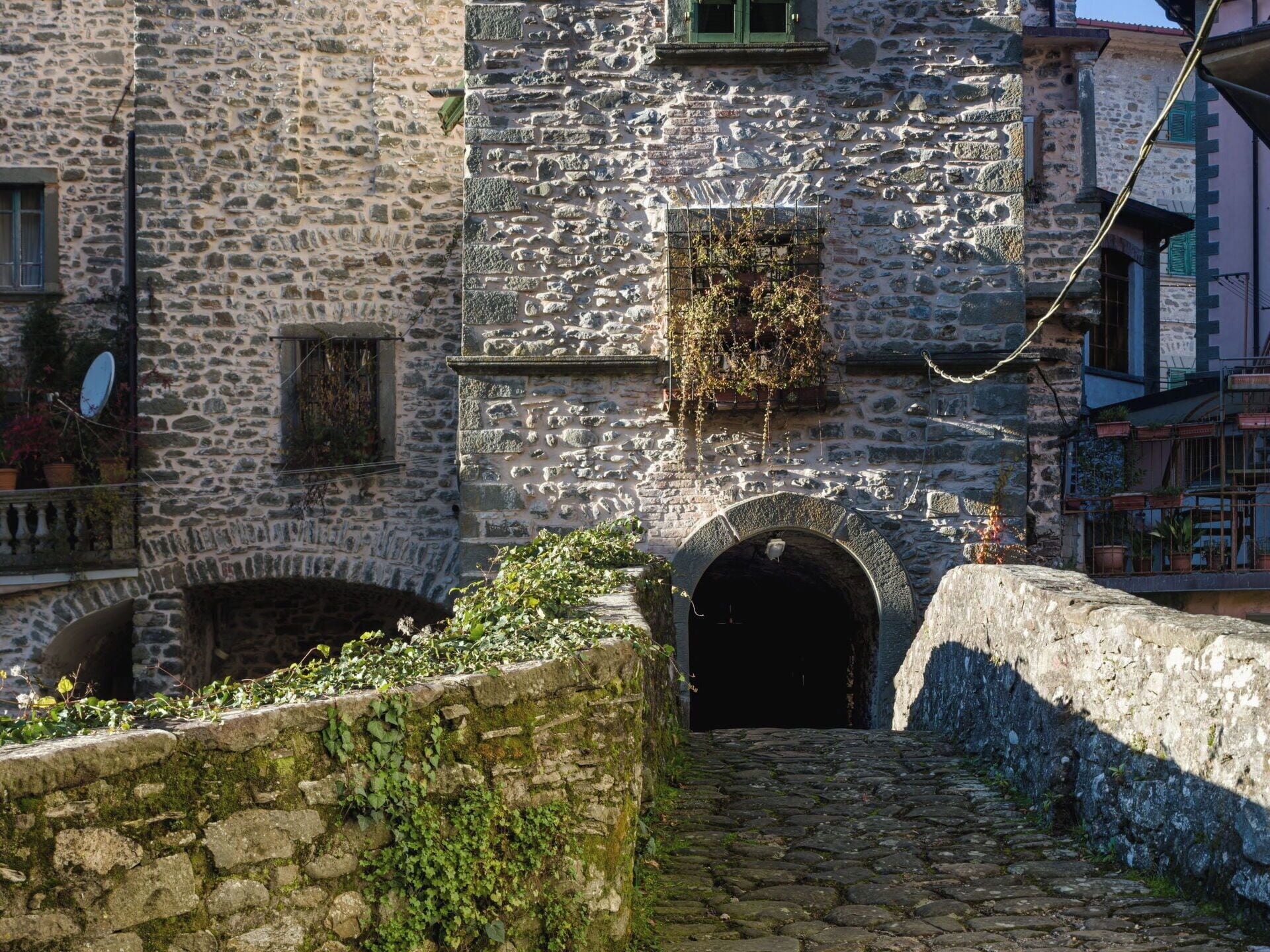 A stone building with a narrow cobblestone path leading to an arched entrance.