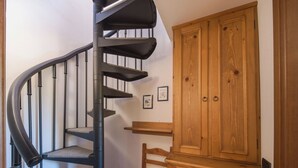 A spiral staircase with a black handrail and carpeted steps, leading to a wooden cabinet with two doors. - Beautiful private villa for 4 people with WIFI and terrace (Bagnone)