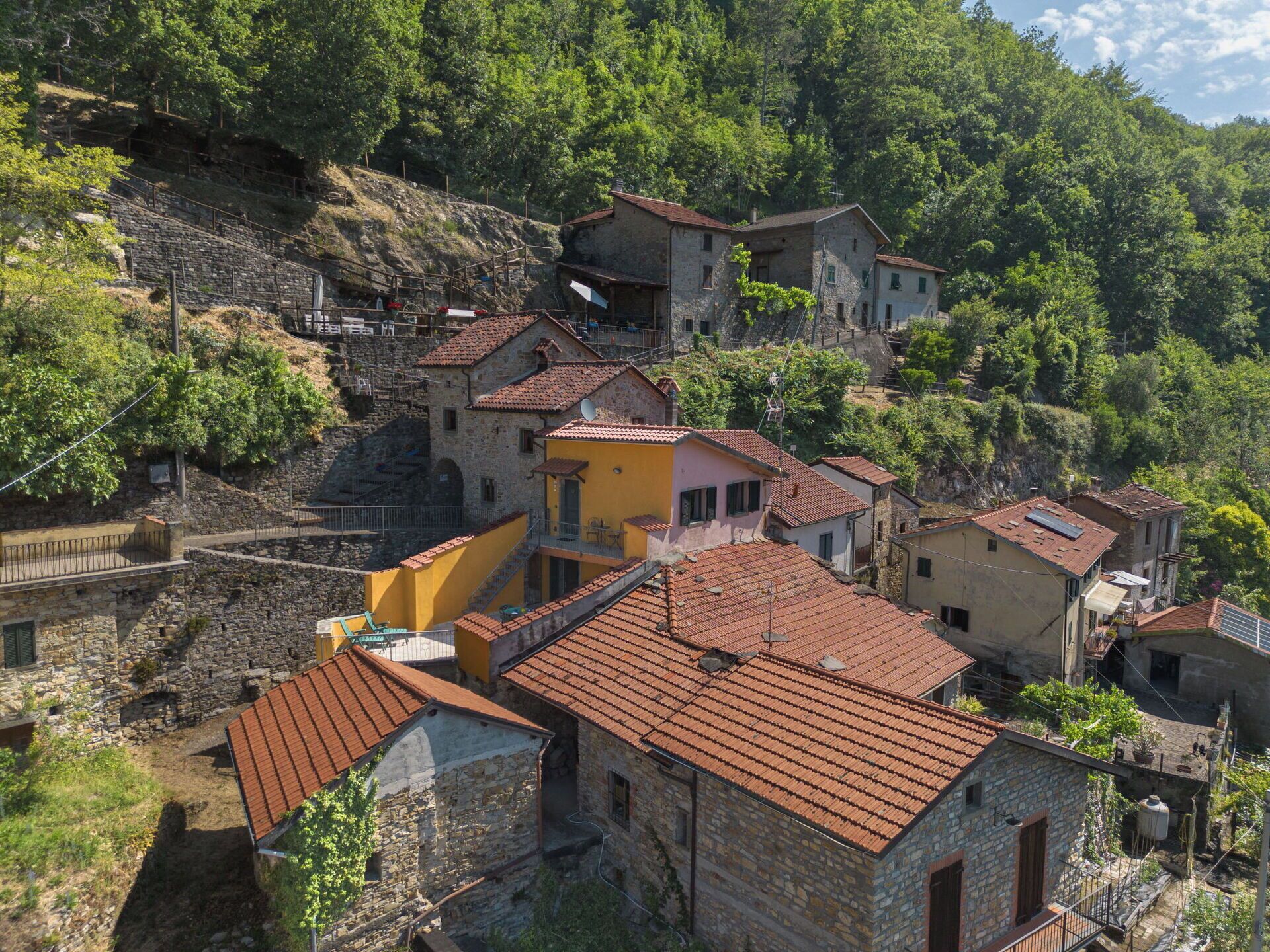 A hillside village with stone buildings and terraced roofs.