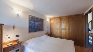 A bedroom with a bed, a nightstand, a lamp, a painting, and wooden wardrobes. - Beautiful private villa for 4 people with WIFI and terrace (Bagnone)