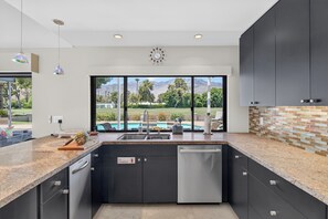 Une cuisine moderne avec vue sur une piscine et des montagnes.