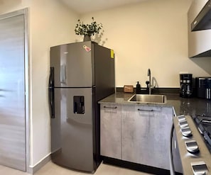 Eine Küche mit einem Edelstahl-Kühlschrank, einer Spüle, einer Kaffeemaschine und einem Herd.