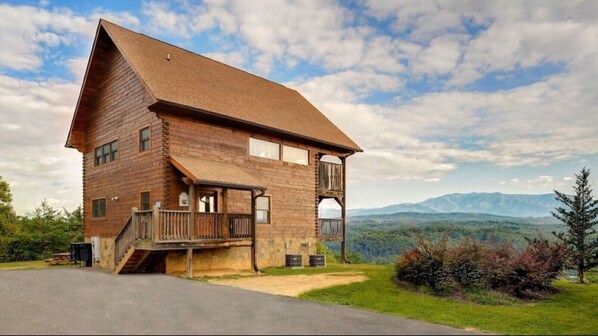 Een houten chalet met een balkon, een veranda en een prachtig uitzicht op de bergen.