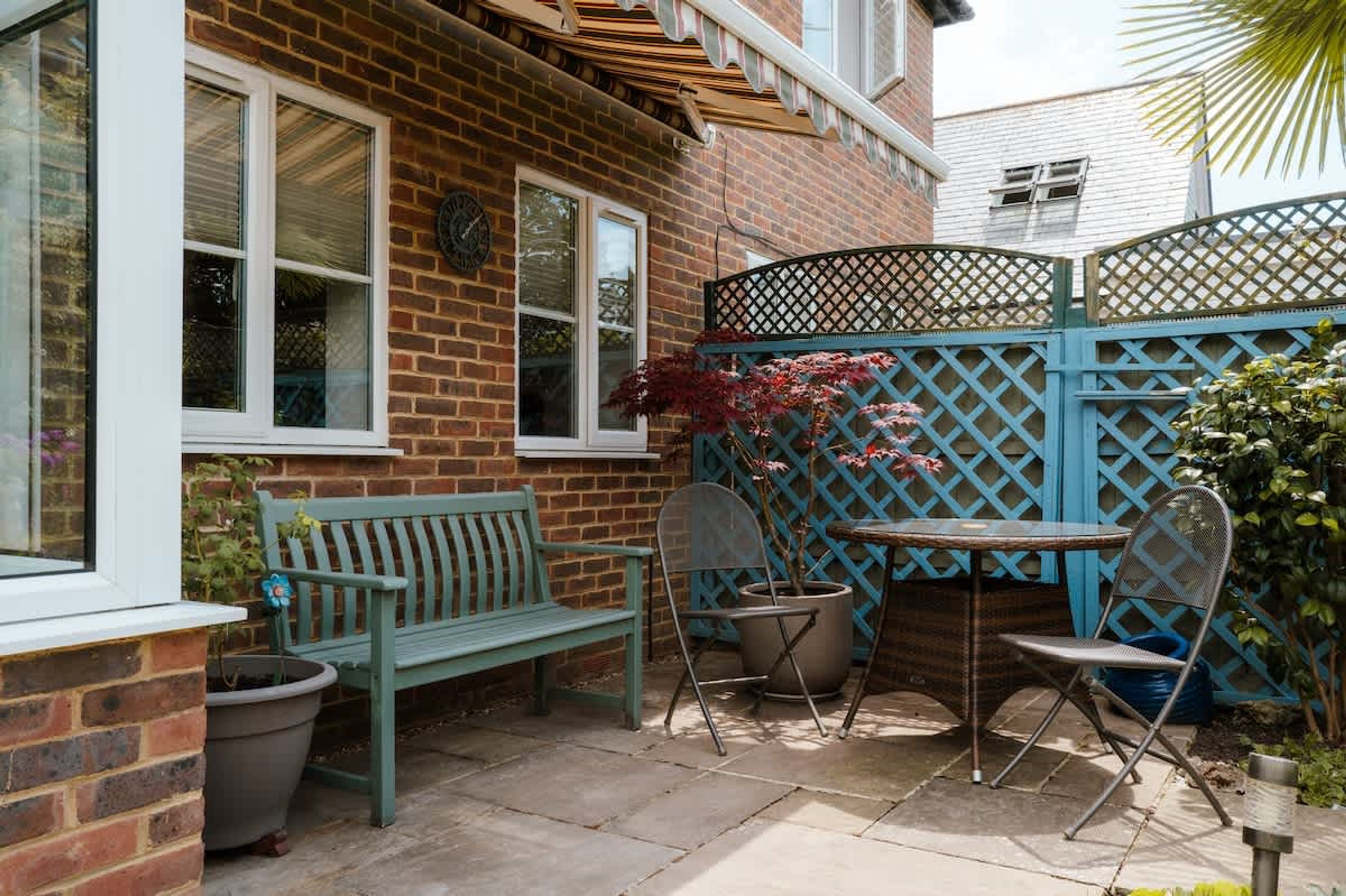 A patio with a bench, chairs, and a table.