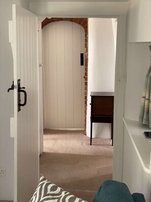A hallway with a white door, a brick wall, and a small table. - April Cottage Seasonal Pool & all year Hot Tub (Hordle)
