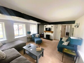 A living room with a sofa, armchair, coffee table, and a fireplace. - April Cottage Seasonal Pool & all year Hot Tub (Hordle)