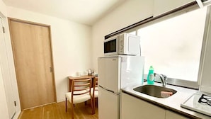 Uma cozinha compacta com micro-ondas, geladeira e pia.