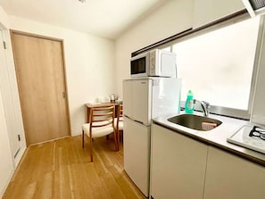 A compact kitchen with a microwave, refrigerator, and sink. - LunaStay Apartments - 103 (東京)